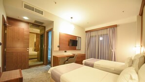 Une chambre d’hôtel avec deux lits, un bureau, une chaise, une télévision et une armoire.