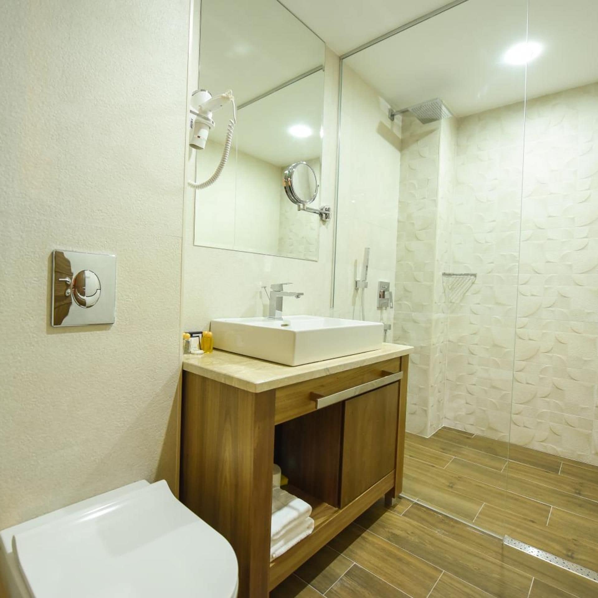 A bathroom with a sink, mirror, and shower.