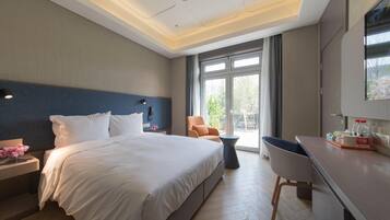 Een hotelkamer met een groot bed, een bureau, een stoel en uitzicht op het omliggende landschap.