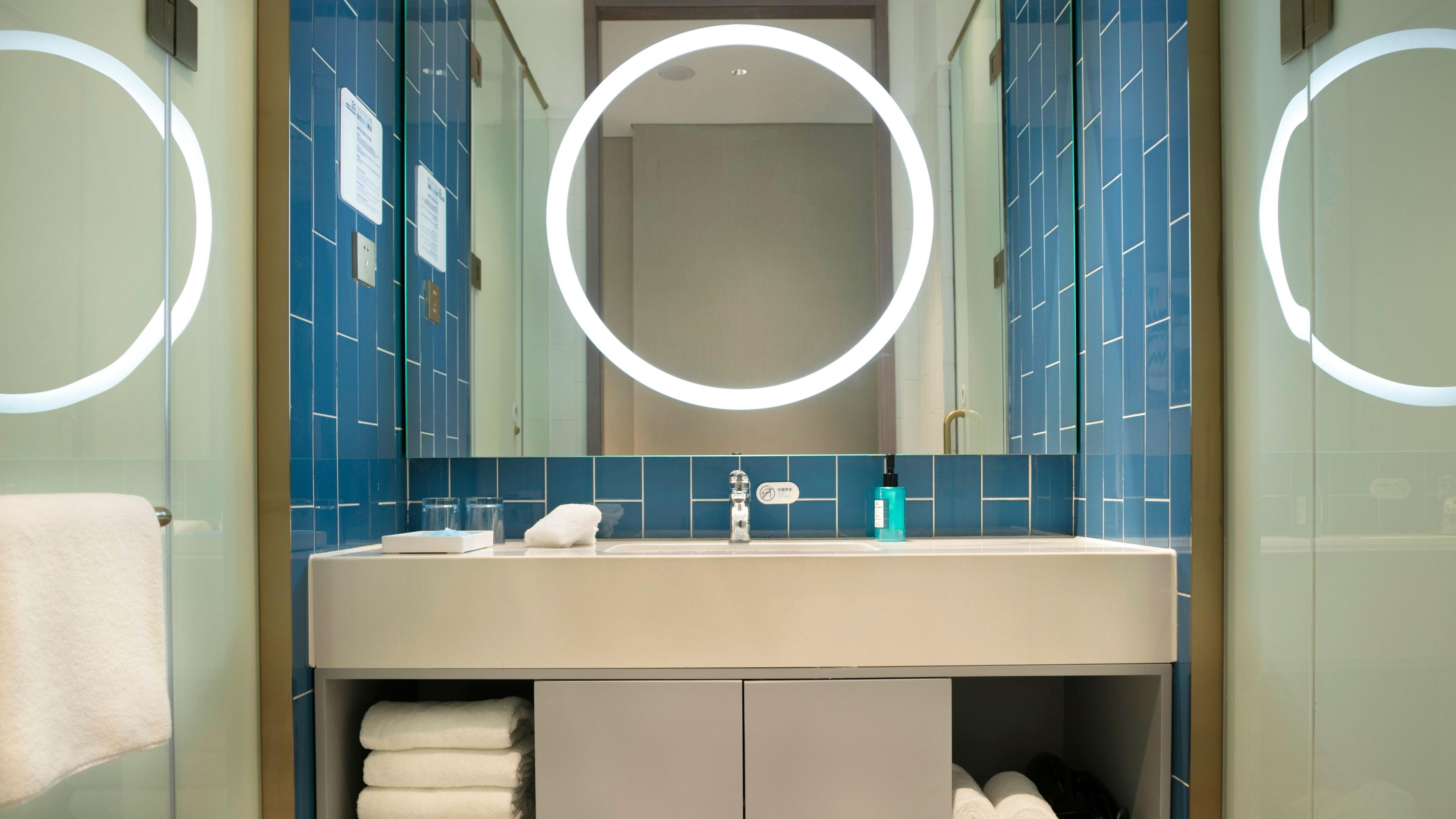 Een moderne badkamer met een grote spiegel, een wastafel en een handdoekhouder.