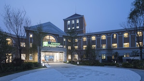 A Holiday Inn Express building with a central tower, large arched windows, and a well-lit entrance.