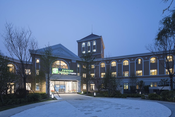 A Holiday Inn Express building with a central tower, large arched windows, and a well-lit entrance.