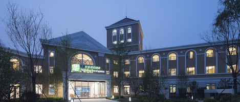 A Holiday Inn Express building with a central tower, large arched windows, and a well-lit entrance.
