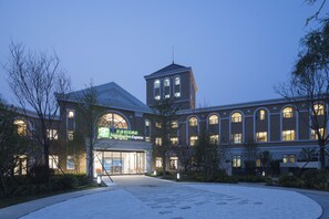 A Holiday Inn Express building with a central tower, large arched windows, and a well-lit entrance. - Holiday Inn Express Beijing Badaling (Yanqing)