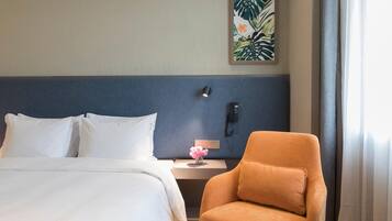 A hotel room with a bed, a nightstand, a phone, a chair, and a wall art piece.