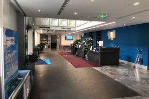 A hotel lobby with a reception desk, a red carpet, and a TV screen.