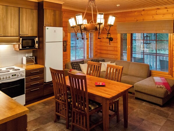 A cozy kitchen with wooden cabinets, a refrigerator, a stove, and a dining table with chairs.