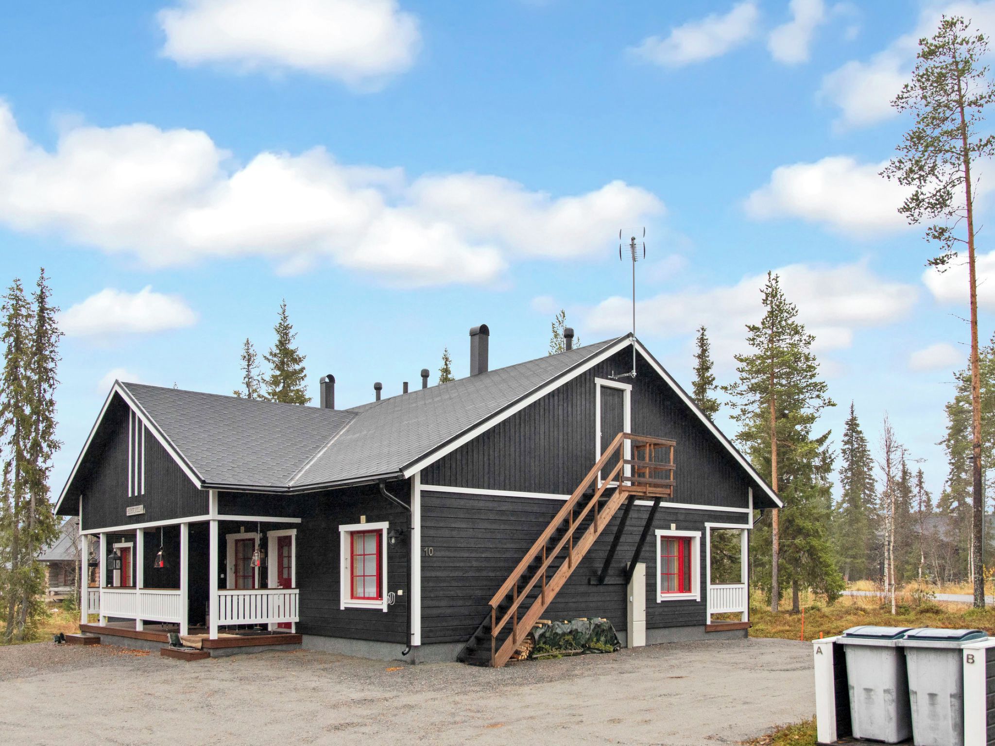 A two-story log cabin with a porch, a chimney, and a wooden staircase.
