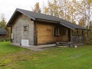 A wooden cabin with a sloped roof, a front porch, and a small deck.
