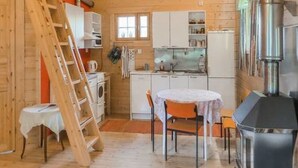Une cuisine de taille réduite, dotée de meubles en bois, d’une cuisinière et d’un coin repas avec une table et des chaises.
