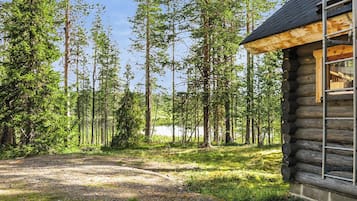 Une cabane en rondins avec une allée en gravier menant à une terrasse en bois.
