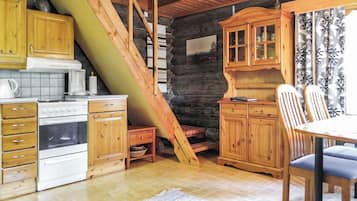 A rustic kitchen with wooden cabinets, a stove, and a clock on the wall.