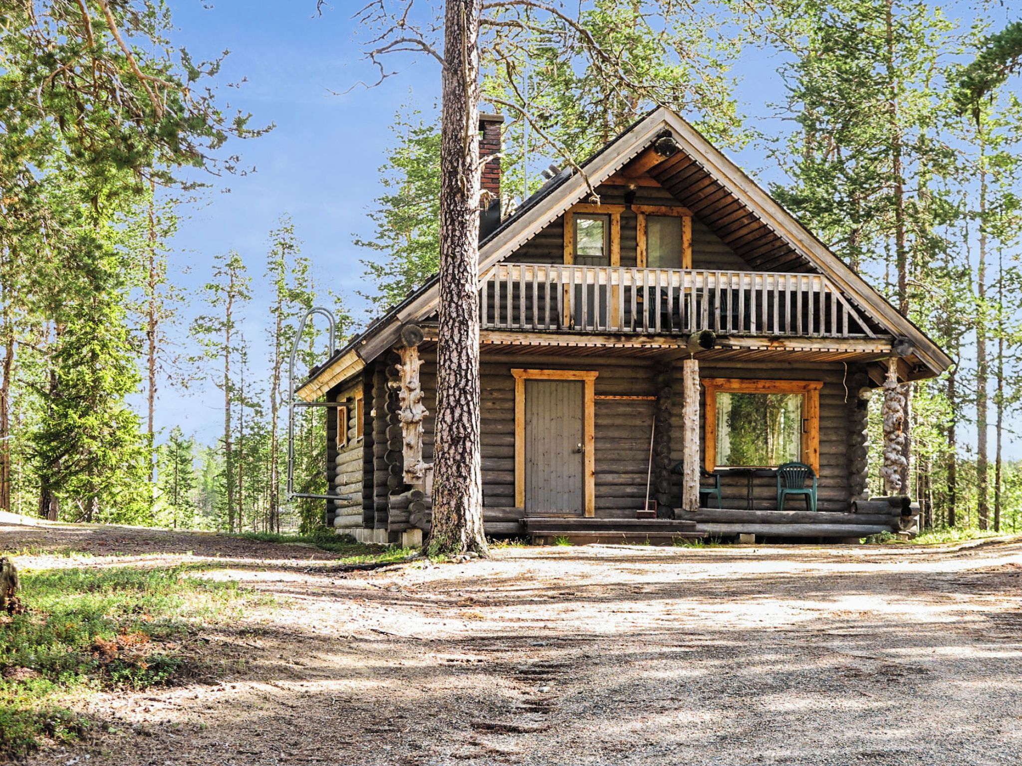 Une cabane en rondins avec un porche, une porte d’entrée et une cheminée.