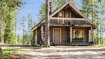 Une cabane en rondins avec un porche, une porte d’entrée et une cheminée.