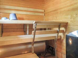 Un sauna en bois avec des bancs et une chaise en métal.