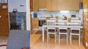Una cucina compatta con mobili in legno, un tavolo da pranzo con sedie e un piano cottura integrato.