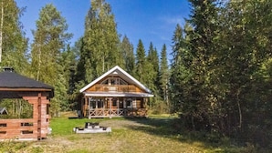 Una baita con un portico, circondata da un bosco.