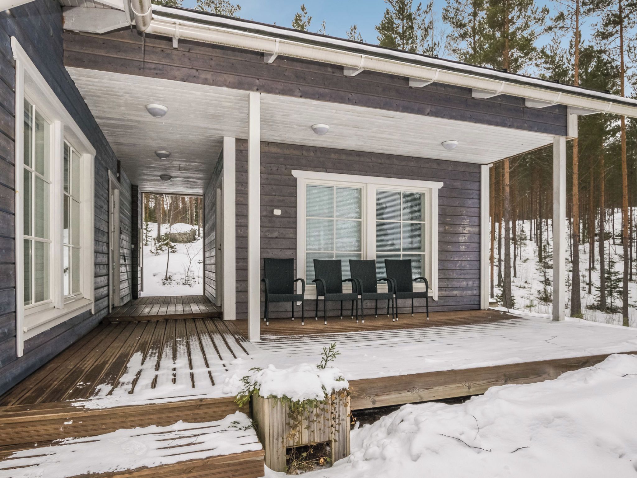 Une véranda avec une terrasse en bois et un espace salon équipé de chaises.
