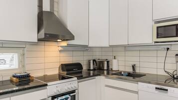 Een moderne keuken met witte kasten, een roestvrijstalen afzuigkap, een inbouwmagnetron en een Siemens vaatwasser.