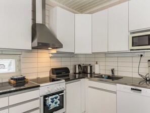 Une cuisine moderne avec des meubles blancs, une hotte en acier inoxydable, un four à micro-ondes encastré et un lave-vaisselle Siemens.