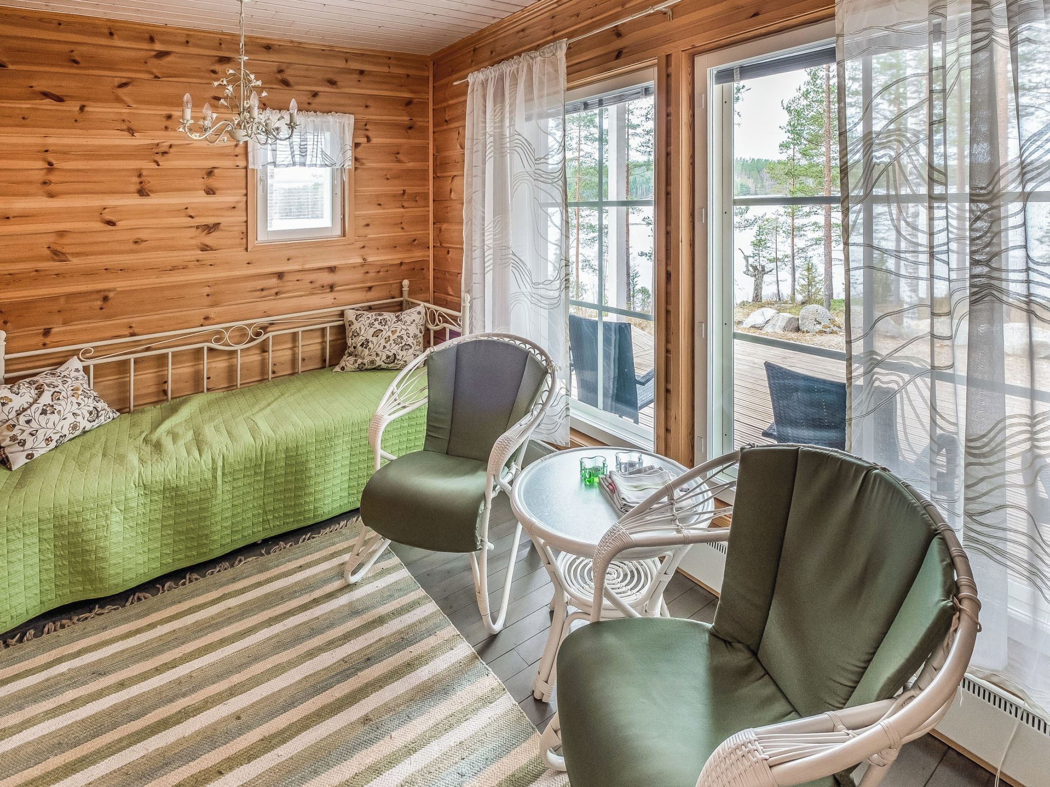 A cozy room with a bed, two chairs, a table, and a window with curtains.