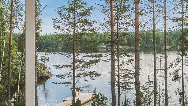 Une terrasse en bois qui mène à un lac paisible, entouré de grands arbres.