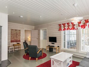 Un salon moderne avec un téléviseur à écran plat, un canapé, une table basse et un tapis rouge.