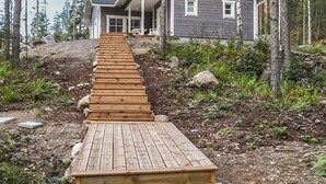 Un escalier en bois menant à une maison entourée d’arbres.