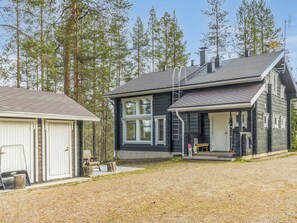En toetages hytte med en overdækket veranda og en garage.