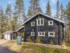 A black wooden cabin with multiple windows and a ladder, surrounded by a forest. - Vacation home Uuvana by Interhome (Äkäslompolo)