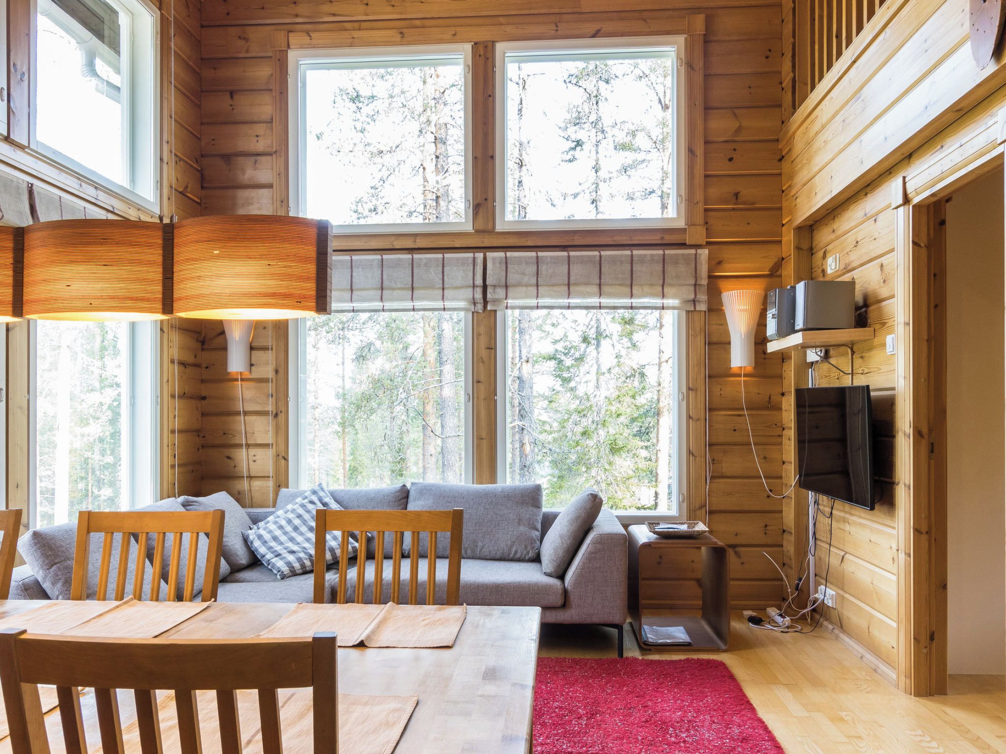 A cozy cabin interior with a sofa, chairs, a dining table, and a TV.