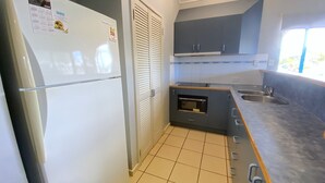 A compact kitchen with a refrigerator, oven, sink, and cabinets. - Osprey Holiday Village Unit 122/2 Bedroom apartment in complex with a pool (EXMOUTH)