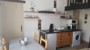 A compact kitchen with a washing machine, microwave, and a small dining area with a polka dot tablecloth. - The charm of wood ... (Écharcon)