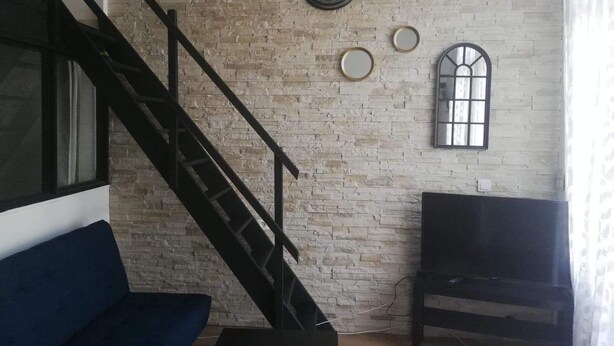 A living room with a staircase, a TV, and a brick wall with mirrors. - The charm of wood ... (Écharcon)
