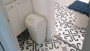 A bathroom with a white sink, toilet, and trash bin. The floor has a black and white patterned tile design. - The charm of wood ... (Écharcon)