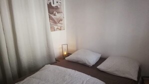 A bedroom with two beds, each with a white pillow and a patterned blanket. There is a nightstand with a lamp between the beds. - The charm of wood ... (Écharcon)