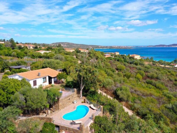 Una villa con piscina rodeada de exuberante vegetación y vistas al mar.