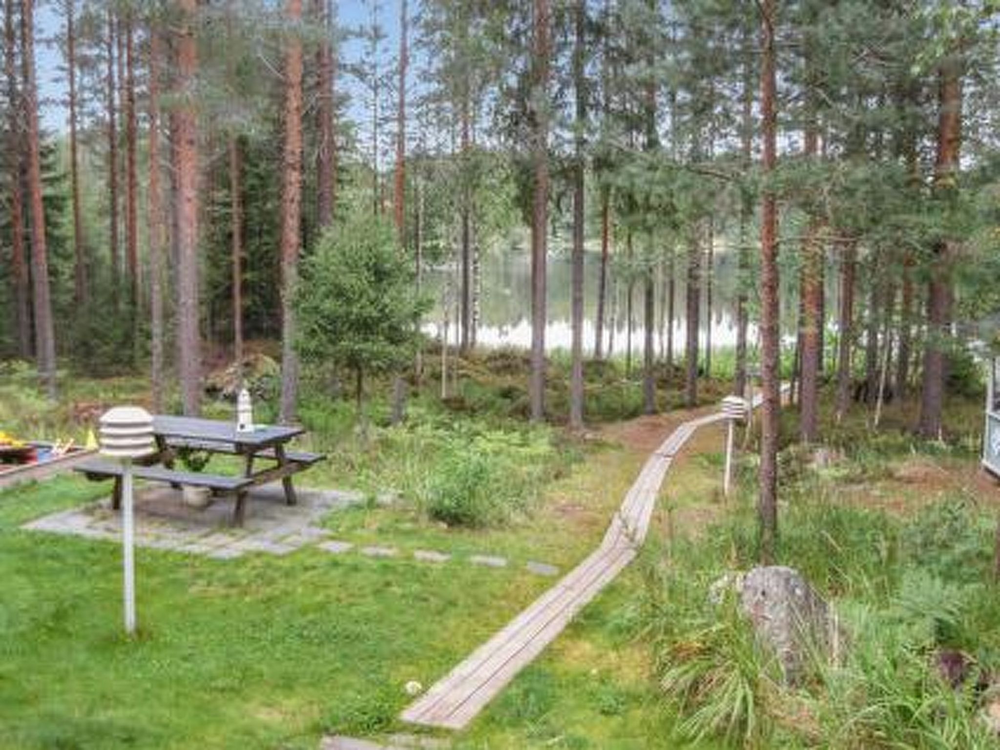 A forested area with a picnic table and a wooden walkway.
