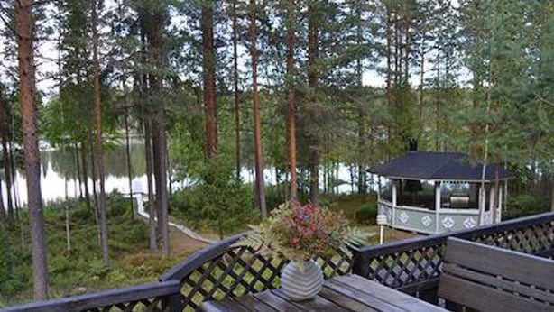 Un patio in legno con un gazebo e un tavolo con un vaso di fiori.