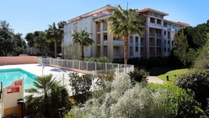 Een meerhoog hotel met zwembad, omgeven door palmbomen en begroeiing.
