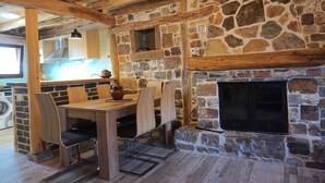 Um interior rústico com lareira de pedra, mesa de jantar de madeira e cadeiras.