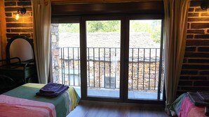 Quarto com duas camas, uma janela com vista para um edifício de pedra e uma cadeira.