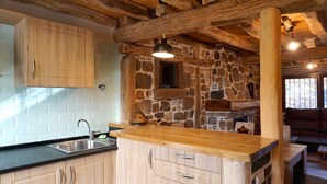 Uma cozinha rústica com armários de madeira, parede de pedra e bancada de madeira.