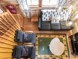 A cozy cabin interior with a wooden ceiling, a sofa with forest-themed pillows, a patterned rug, and a small table. - Riekonmarja by Interhome (Äkäslompolo)