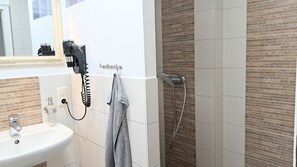 Une salle de bain équipée d’un lavabo, d’un sèche-cheveux, d’une serviette et d’une douche.