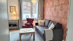 Un salon comprenant un canapé, un fauteuil, une table basse et une lampe.