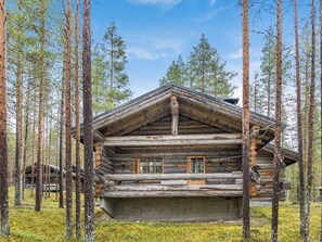 A log cabin surrounded by tall pine trees. - Ylläsnäkyy 7 / karkelo by Interhome (Äkäslompolo)