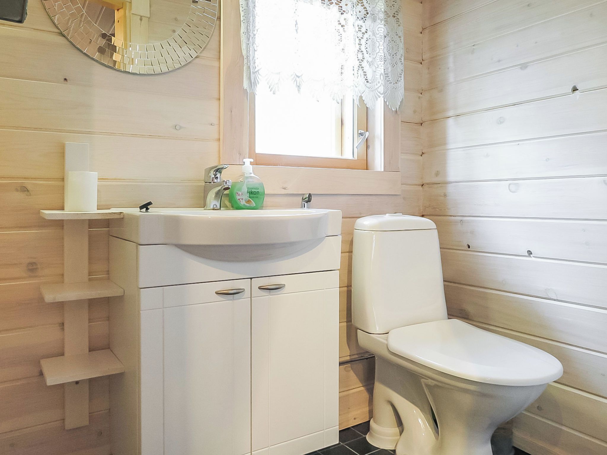 A bathroom with a white sink, a toilet, and a mirror with a decorative frame.