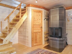 A wooden interior with a fireplace, a wooden door, and a staircase. - Vacation home Ruska by Interhome (Raattama)
