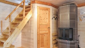 A wooden staircase leading to a door, a fireplace with a tiled surround, and a patterned rug on the floor. - Vacation home Ruska by Interhome (Raattama)